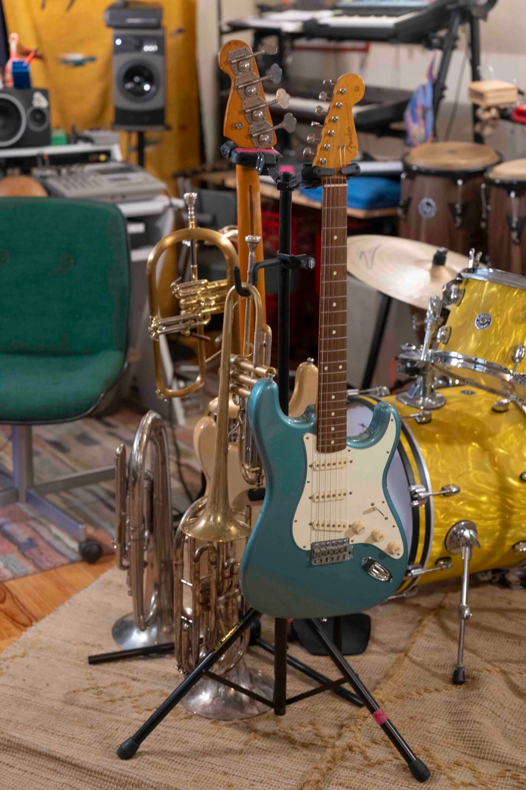 Guitares électriques Fender, trompettes et cor, posés sur des pieds devant une batterie dorée, dans le studio d'enregistrement de Voyou à Pantin